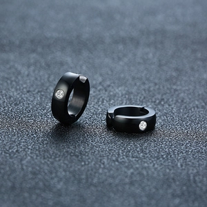 Vue macro de boucles d'oreilles créoles noires en acier poli avec un petit zircon