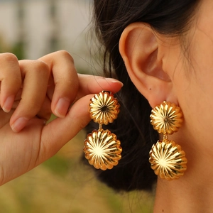 Boucles d'oreilles dorées à double couche avec texture radiale portées par mannequin