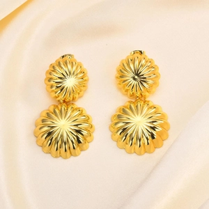 Gros plan de boucles d'oreilles pampilles en or 18 carats avec motif soleil sur soie beige