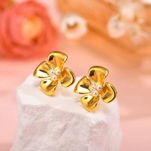 Detail of flower earrings with gold petals and pearls on a white stone base