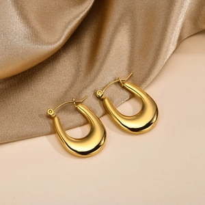 Detail view of golden U-shaped horseshoe earrings with high-polished mirror finish