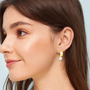 Elegant gold hoop earrings with white pearls on female model for a chic look