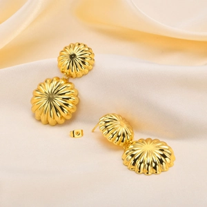 Boucles d'oreilles pendantes en cuivre plaqué or 18 carats sur un élégant fond en soie