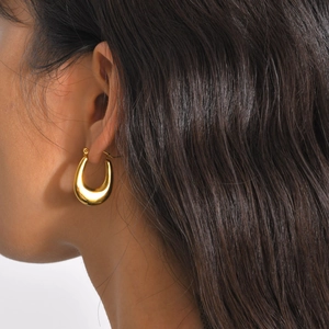 Detail of polished gold U-shaped hoop earring on model with mirror finish shine