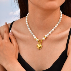 Französische Perlenkette mit goldenem Herzanhänger und OT-Verschluss an einem Model