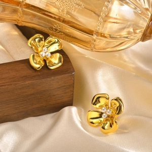 Elegant gold flower earrings with pearls displayed on silk fabric and wooden block