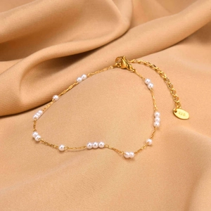 Detailed macro view of gold-plated anklet with small white pearls and K18 metal tag