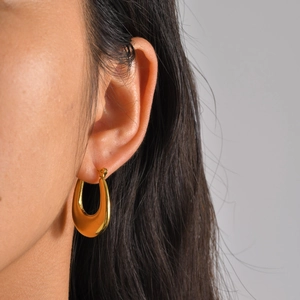 Macro view of gold-plated U-shaped thick hoop earrings worn by a model in profile