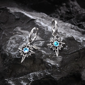 Macro shot of Celtic moon star earrings with blue moonstone on dark natural rock
