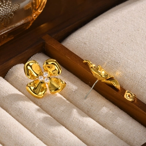 Detailed close-up of golden flower stud earrings with four pearls in a luxury display box