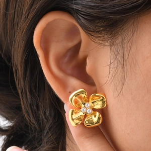 Close-up of a gold flower earring with pearls on a model, showing elegant metal texture