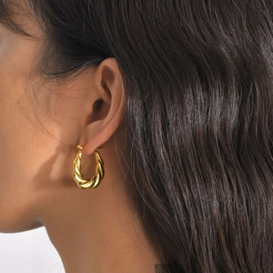 Close-up of a gold-plated twisted rope hoop earring worn on a model's ear