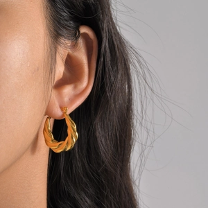 Close-up of gold-plated twisted hoop earrings showing fine spiral texture on model