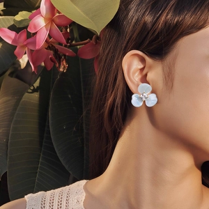 Boucles d'oreilles fleur en résine bleue avec zircon carré portées par un modèle