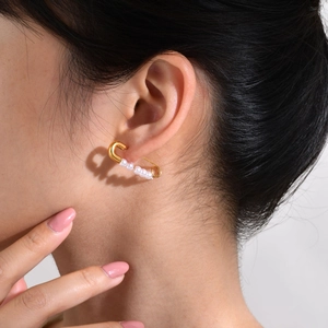 Close-up of gold safety pin earrings with five white pearls worn on a female model