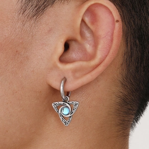 Macro shot of silver Celtic knot triangle earring with blue moonstone on male ear