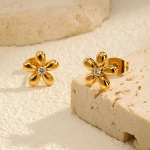 Detail of 18K gold stainless steel flower earrings with clear zircon center on a stone
