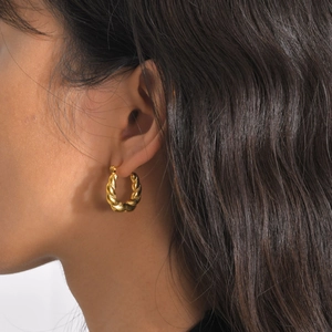 Close-up of golden twisted rope earrings on a female model with dark curly hair