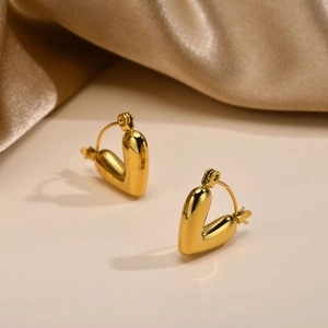 Detailed view of 3D puffy gold heart hoop earrings on elegant champagne silk fabric