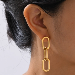 Boucles d'oreilles pendantes à trois maillons en acier inoxydable doré sur un modèle