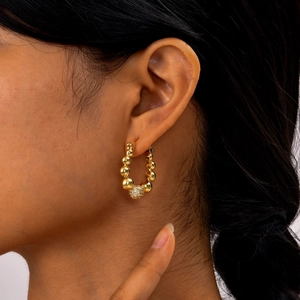 Créoles dorées en perles avec boule sertie de zircons portée par un mannequin