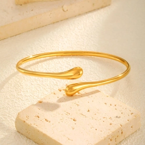 Détail d'un bracelet jonc doré minimaliste en forme de goutte sur socle pierre