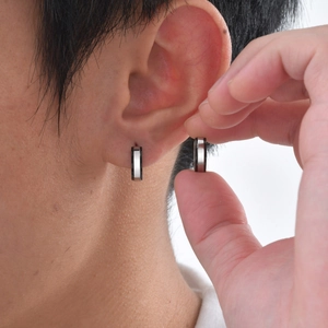 Détail de créoles en acier inoxydable argent et noir portées sur l'oreille