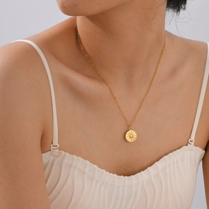 Close-up of golden sunburst pendant necklace worn by model in minimalist setting