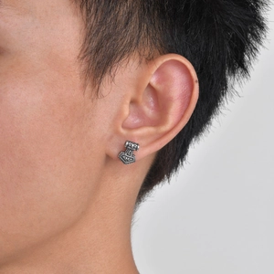 Close-up of a vintage Thor's Hammer stud earring worn on a male ear in retro silver