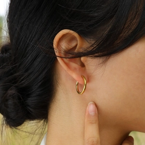 Gros plan de créoles minimalistes plaquées or 18 carats portées par un mannequin
