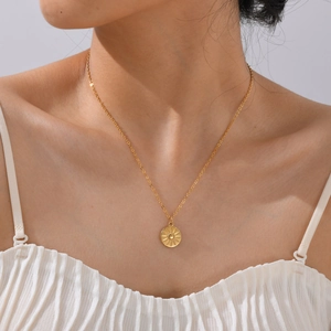 Minimalist gold stainless steel round sunburst pendant necklace worn by a female model