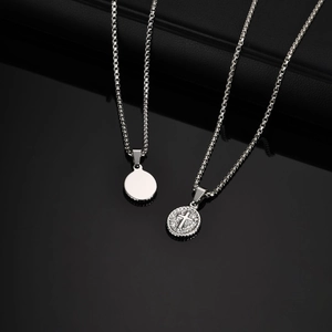 Detailed macro view of silver steel pendants with cross relief and round polished plates