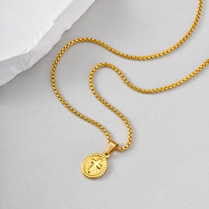 Macro detail of golden oval cross pendant with embossed texture on a box chain