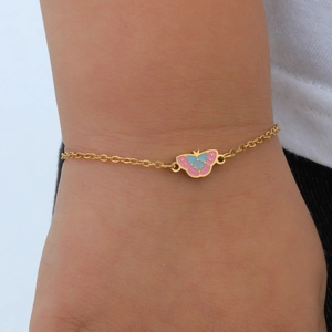 Detail macro van de 18K gouden vlinderarmband met roze en blauw emaille op de pols