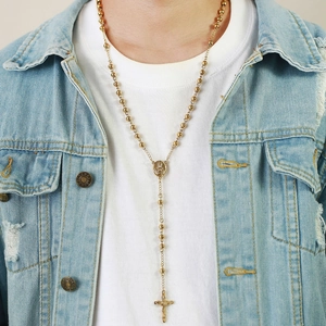 Close-up of golden rosary necklace with a cross pendant worn on a denim jacket