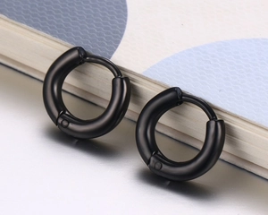 Gros plan de créoles noires minimalistes en acier titane pour un style unisexe