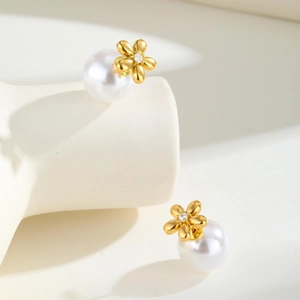 Makroaufnahme von goldenen Blumenohrringen mit weißen Perlen und Zirkonia-Akzenten