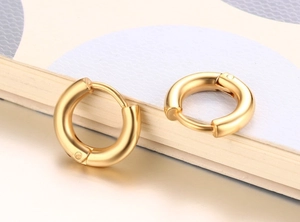 Vue macro de boucles d'oreilles créoles dorées minimalistes avec fini métal mat