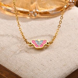 Detailopname van vlinderhanger ketting met roze en blauw emaille op gouden ketting