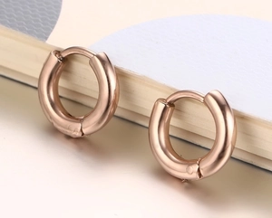 Détail de boucles d'oreilles huggie en or rose poli avec fermoir invisible
