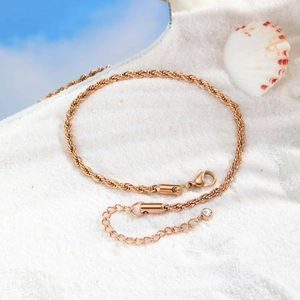 Bracelet de cheville torsadé or rose avec cristal scintillant sur sable blanc