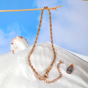 Détail de la chaîne torsadée or rose avec fermoir mousqueton et zircon sur la plage