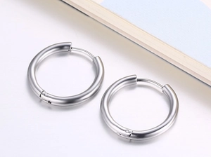 Vue détaillée de créoles en argent poli avec charnière sur un fond minimaliste épuré