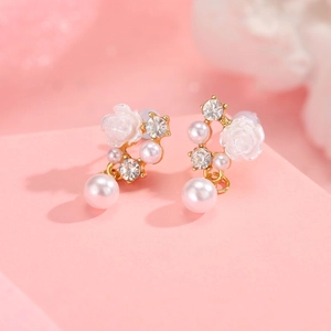 Detailed close-up of camellia flower earrings with faux pearls and rhinestones