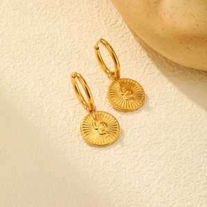 Gros plan sur les boucles d'oreilles médaillon serpent en acier doré 18 carats