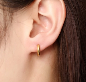Gros plan d'une boucle d'oreille créole minimaliste en acier doré sur un mannequin