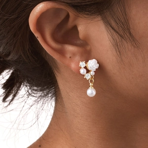 Detail view of pearl camellia drop earrings worn by a model in a close-up profile shot