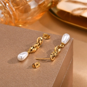 Elegant gold chain drop earrings with white teardrop pearls on a textured gift box