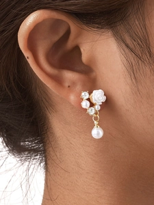 Close-up of golden camellia earrings with white resin rose and pearl drop on ear