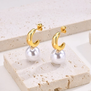 Boucles d'oreilles créoles en acier avec grandes perles blanches sur marbre